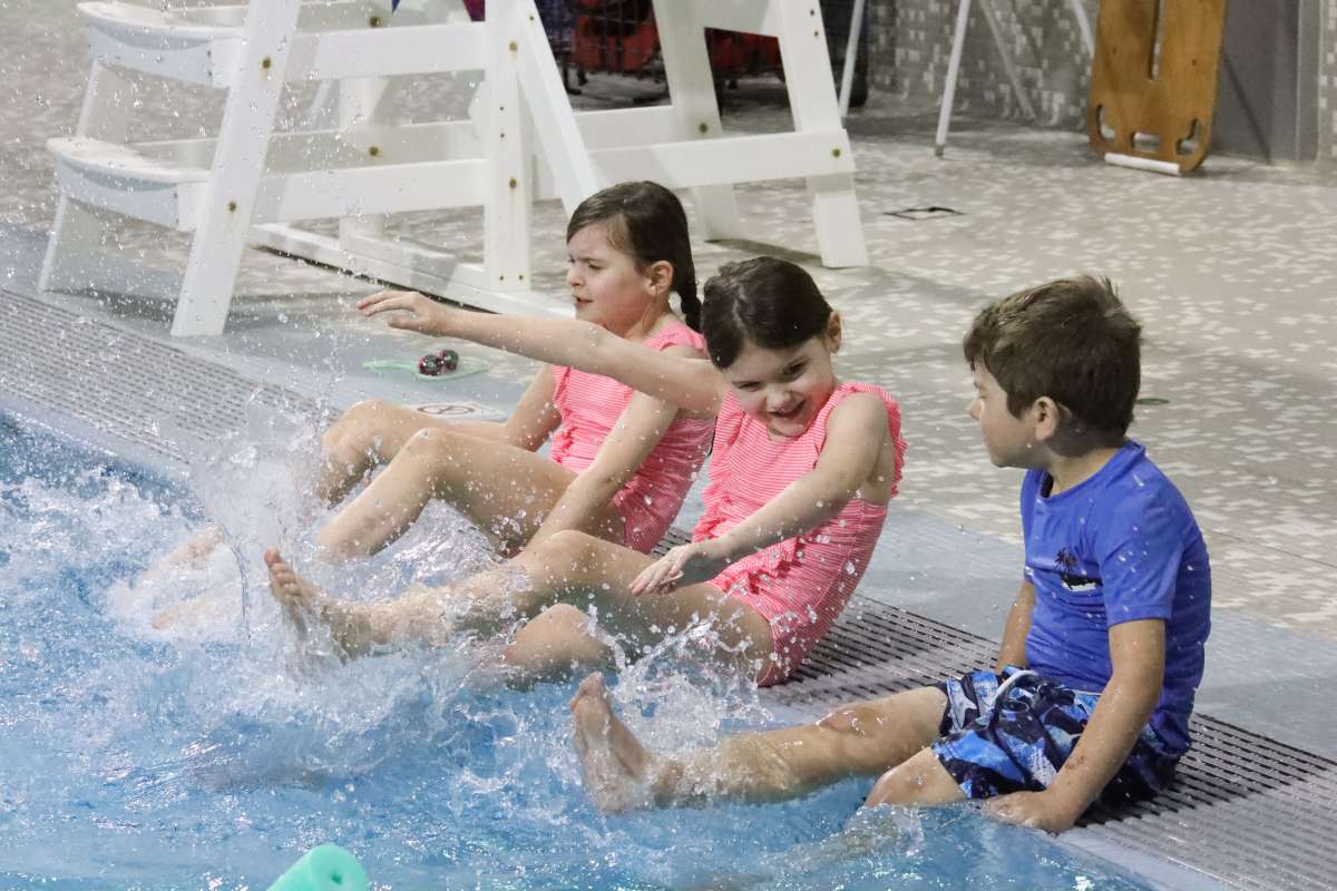 a photo with three kids playing at the state gym pool